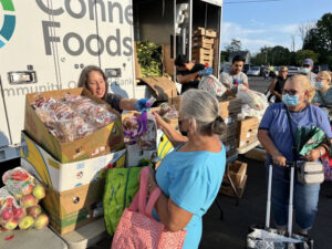 A volunteer from Macedonia Church in Norwalk provides food to a neighbor in line at a Connecticut Foodshare mobile food pantry.